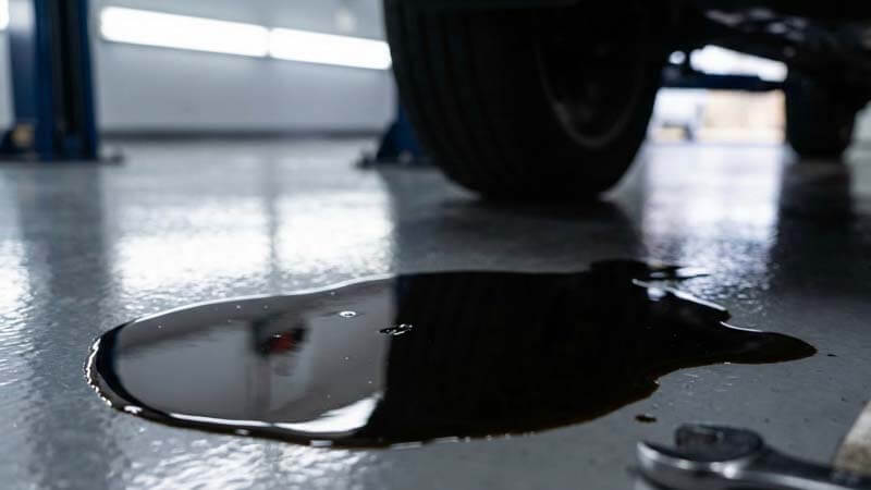 Пятно отработанного масла на чистом полу сервиса рядом с гаечным ключом