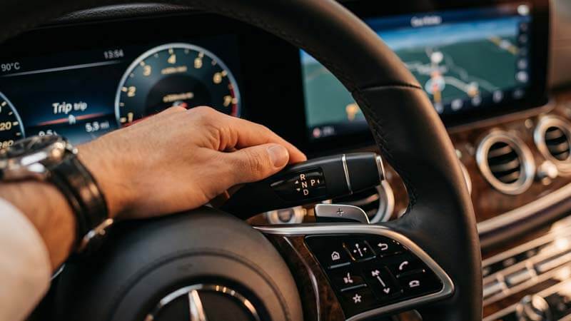 Рука водителя на селекторе передач в салоне Мерседес